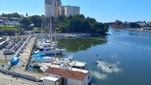 Un port de plaisance avec des bateaux amarrés, un bâtiment en arrière-plan et un ciel dégagé.