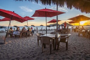 Ein Restaurant direkt am Strand mit Außenbereich und roten Sonnenschirmen.