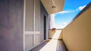 A narrow corridor with a tiled floor, a door with horizontal slats, and a potted plant on a balcony. - Studio in the city center with private parking (AREZZO)