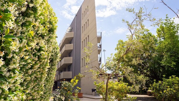 A modern building with multiple balconies, surrounded by lush greenery and trees. - Studio in the city center with private parking (AREZZO)
