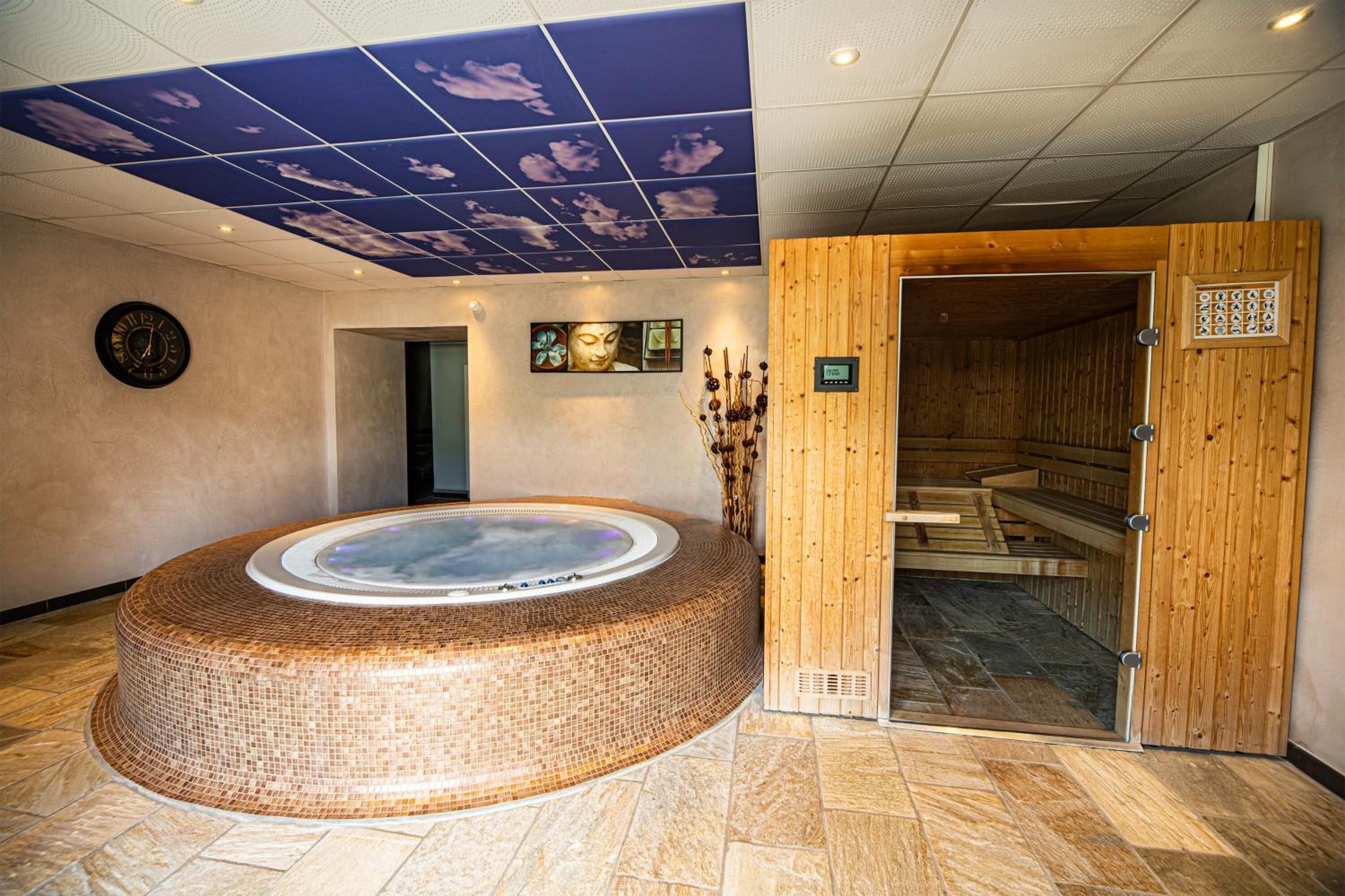 Un área de spa con una bañera de hidromasaje circular, paneles de madera y un techo con diseño de nubes.