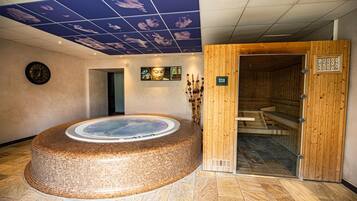 Un área de spa con una bañera de hidromasaje circular, paneles de madera y un techo con diseño de nubes.