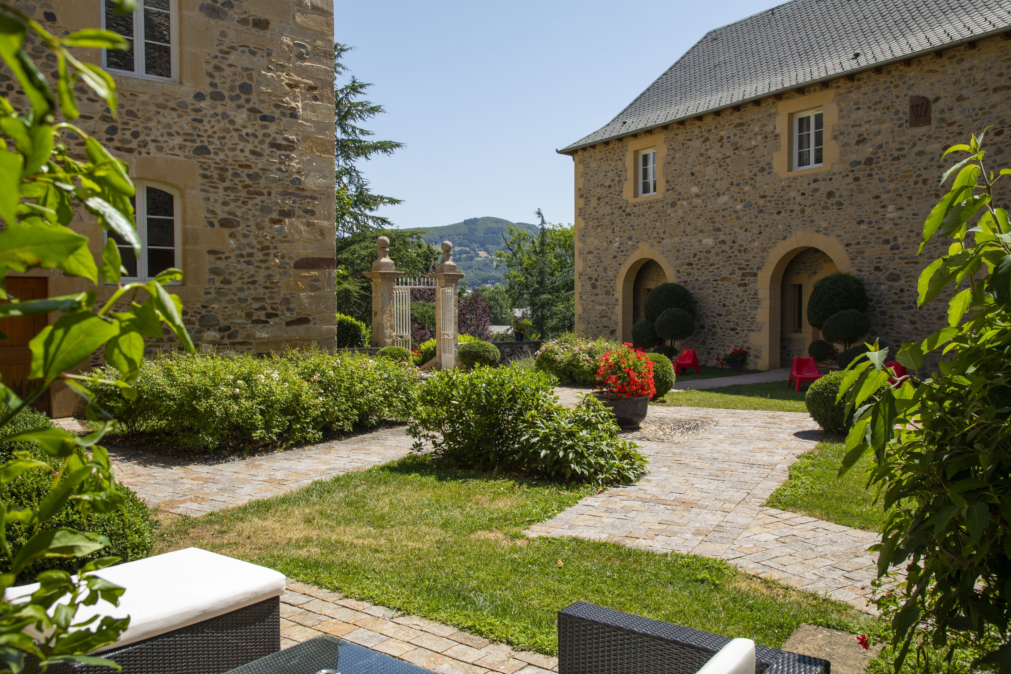 Un edificio de piedra con patio empedrado, mobiliario exterior y vistas del paisaje circundante.