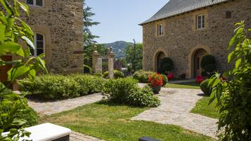 Un edificio de piedra con patio empedrado, mobiliario exterior y vistas del paisaje circundante.