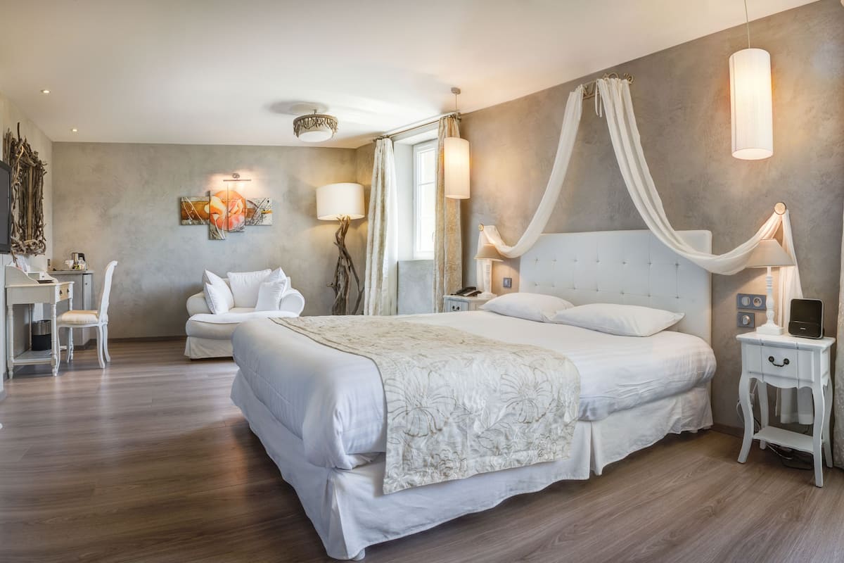 A modern bedroom with a large bed, bedside tables, a desk, and a chair.