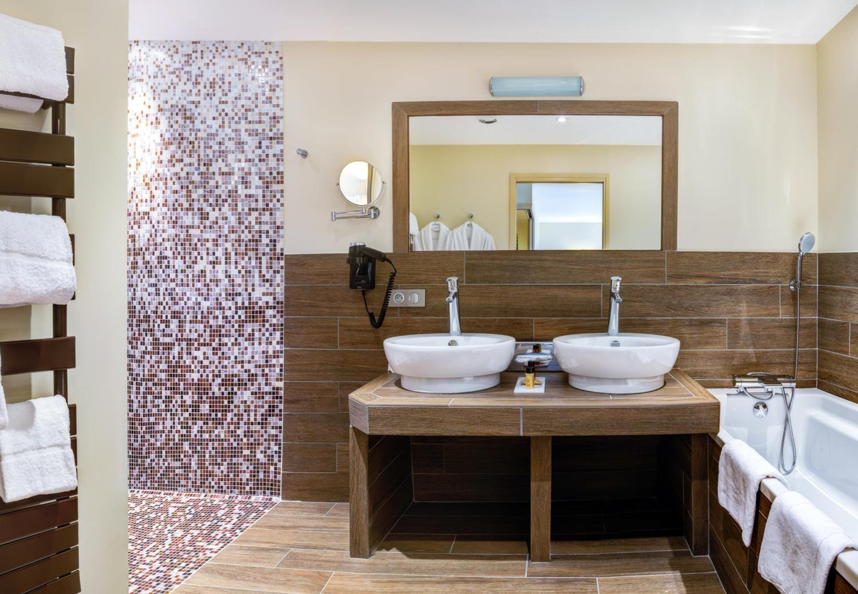 Une salle de bain avec deux lavabos, un miroir et une douche.