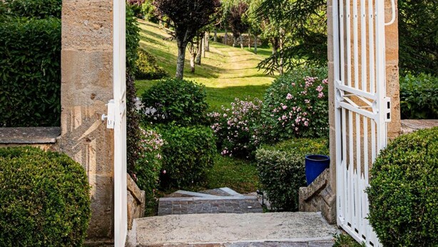 A stone archway with a white gate leading to a garden. - Château de la Falque, The Originals Relais  (Saint-Geniez-d'Olt-et-d'Aubrac)