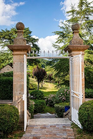 A stone archway with a white gate leading to a garden. - Château de la Falque, The Originals Relais  (Saint-Geniez-d'Olt-et-d'Aubrac)