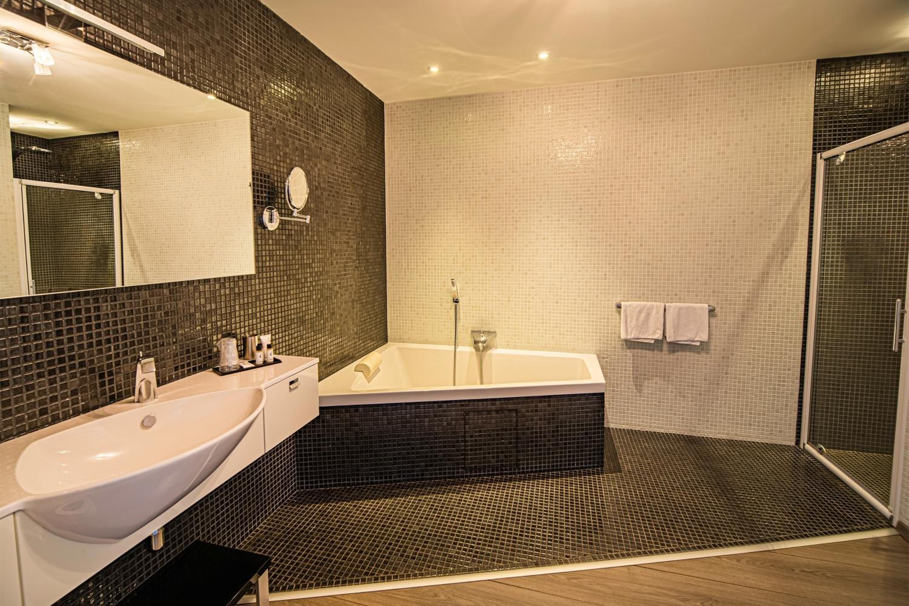 Un baño moderno con un lavamanos grande y blanco, una bañera independiente y una ducha a ras de suelo.