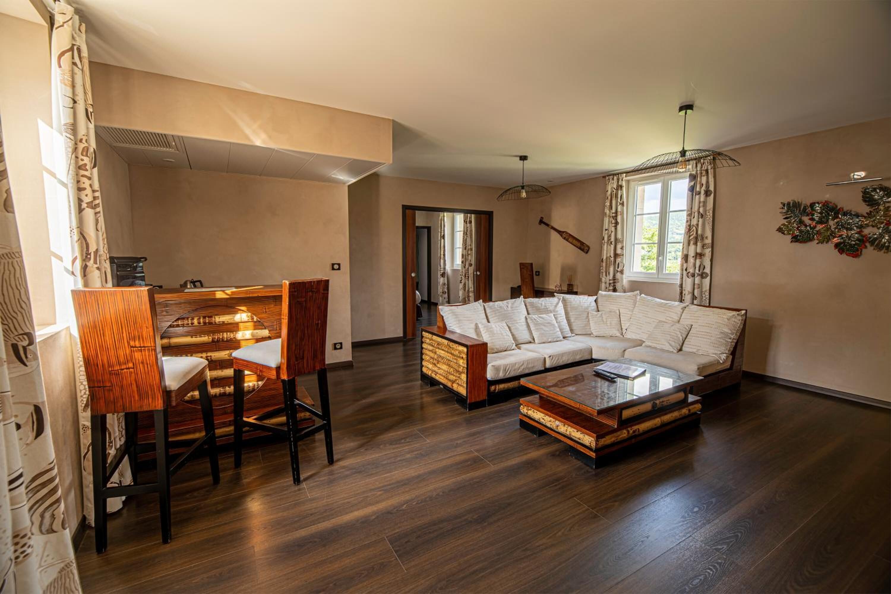 A spacious living room with a wooden coffee table, a white sofa, and a dining area with wooden chairs.