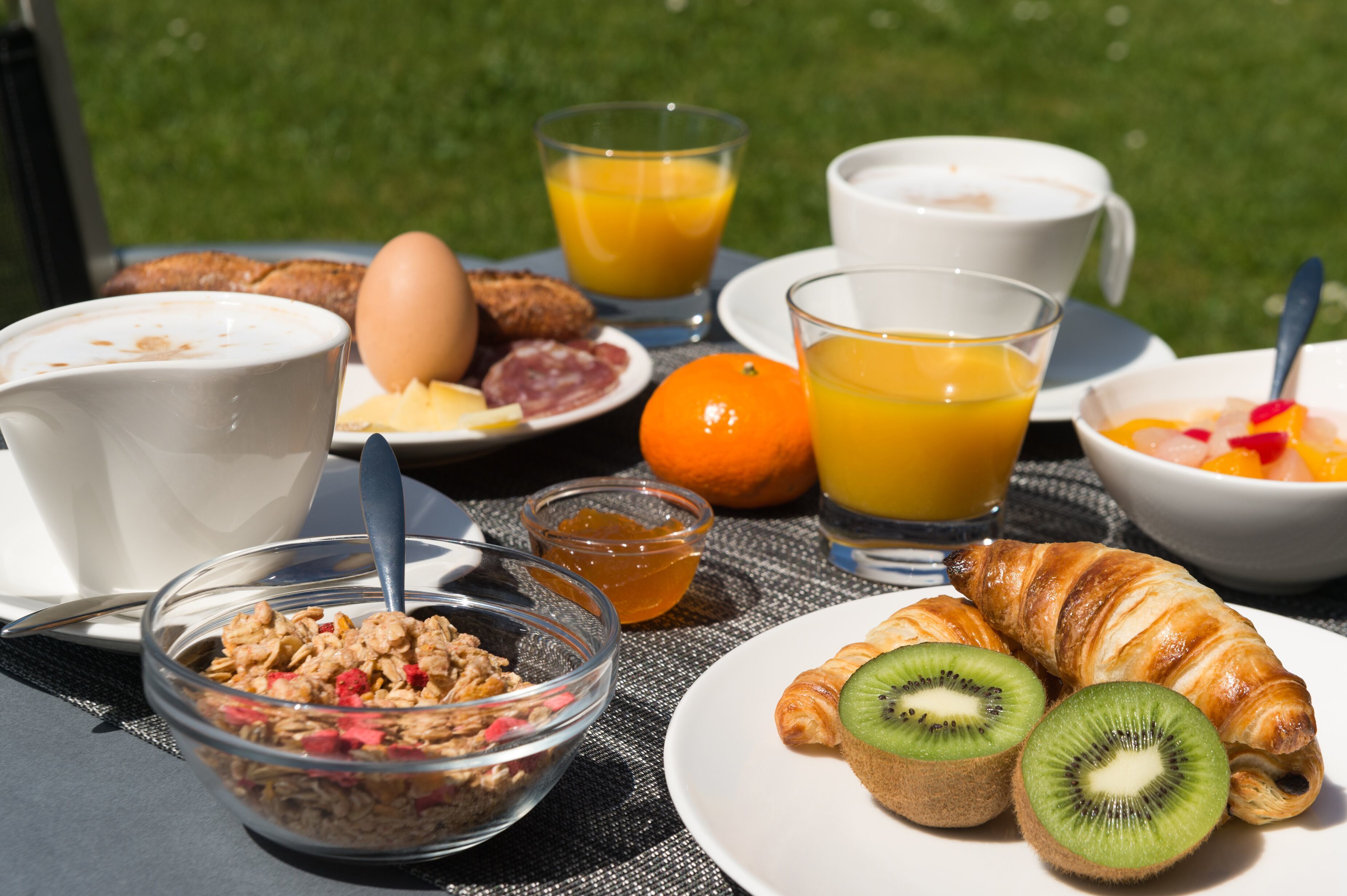 Et morgenbord med croissanter, kiwiskiver, appelsinjuice og cornflakes.