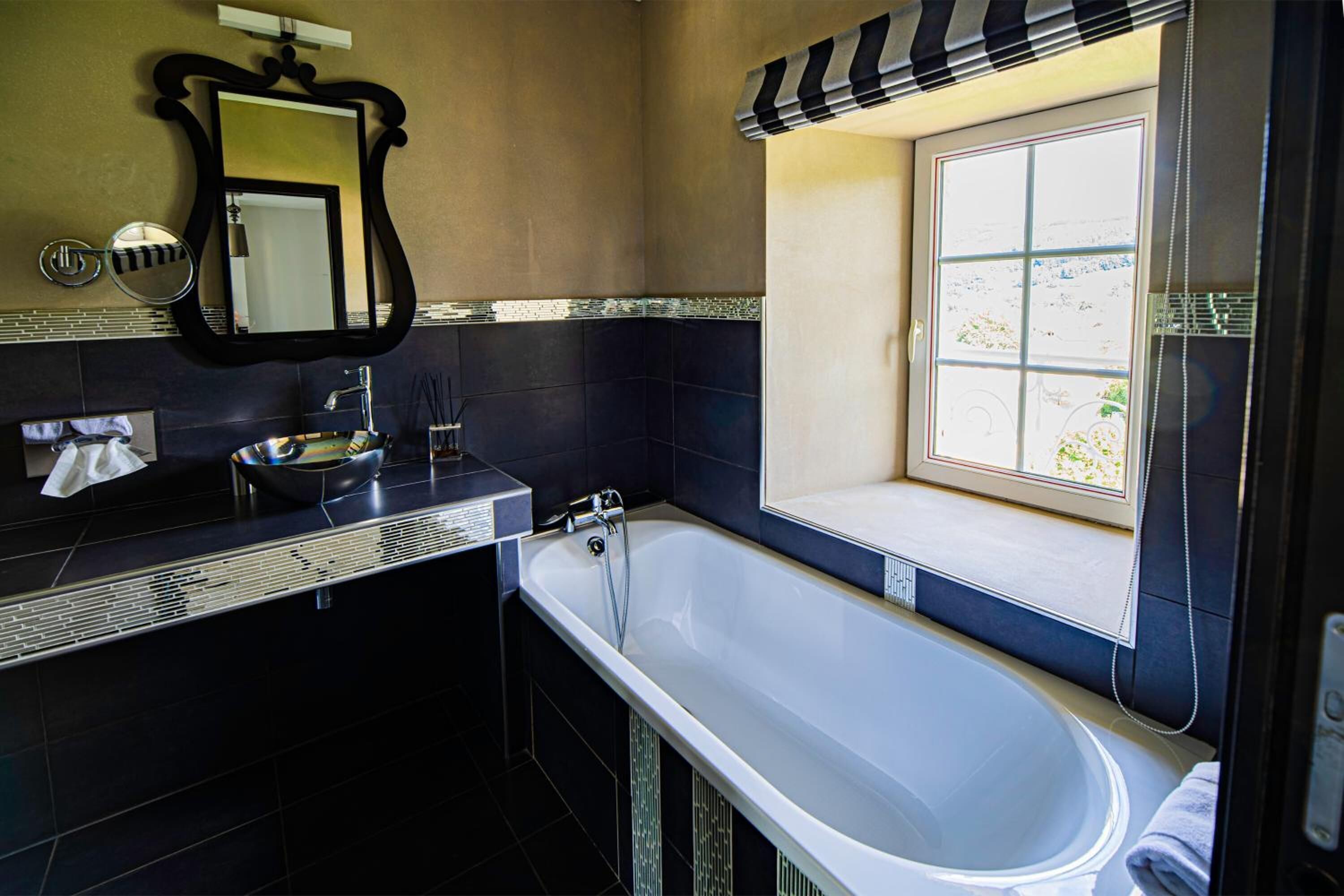 A modern bathroom with a large bathtub, a vanity with a mirror, and a window providing natural light.