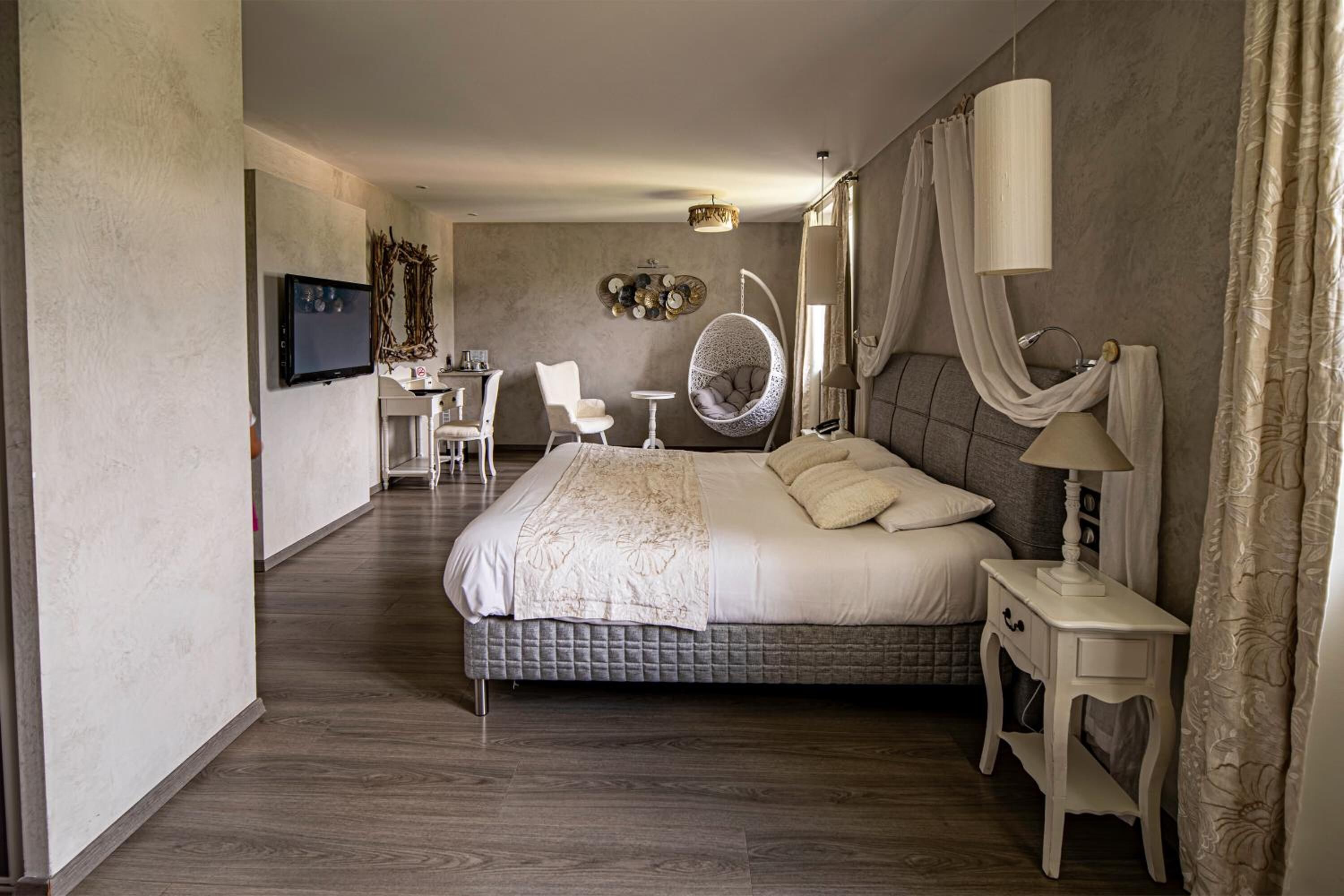A modern hotel room with a large bed, a desk, a chair, and a television.