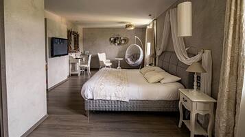 A modern hotel room with a large bed, a desk, a chair, and a television.