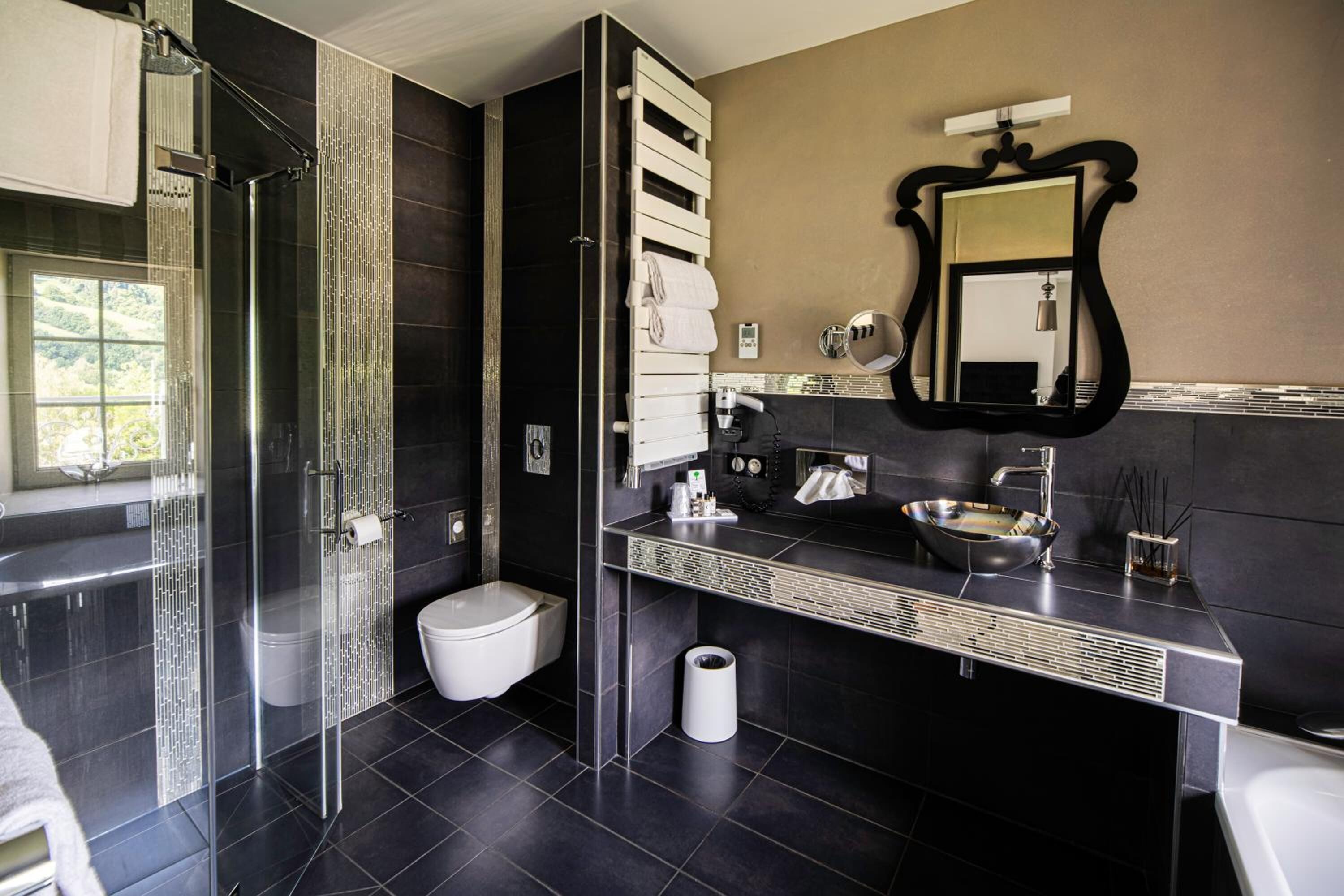 Un baño moderno con cabina de ducha de vidrio, inodoro, lavamanos y espejo.