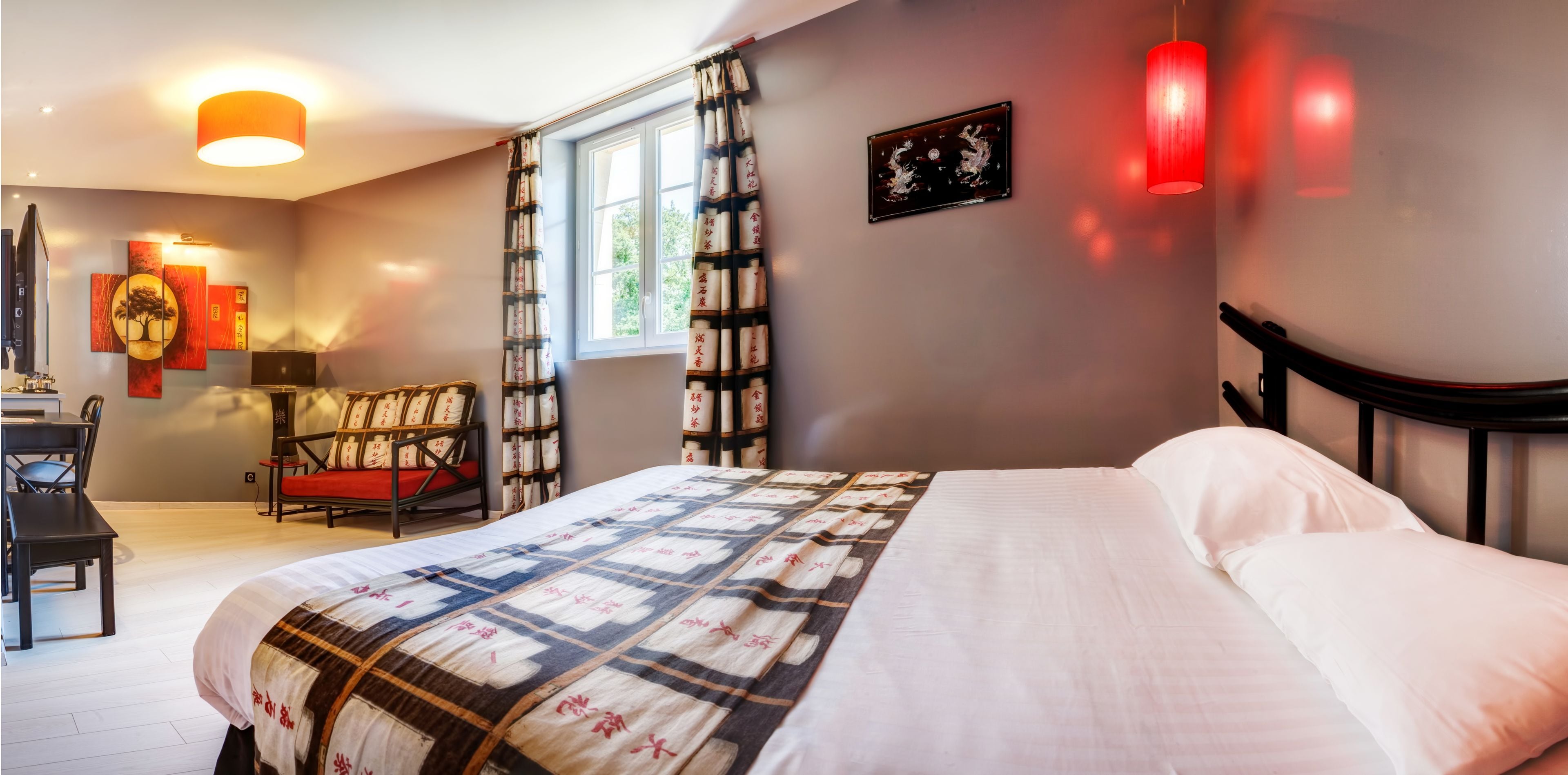 A bedroom with a bed, a desk, a chair, a window, and artwork on the walls.