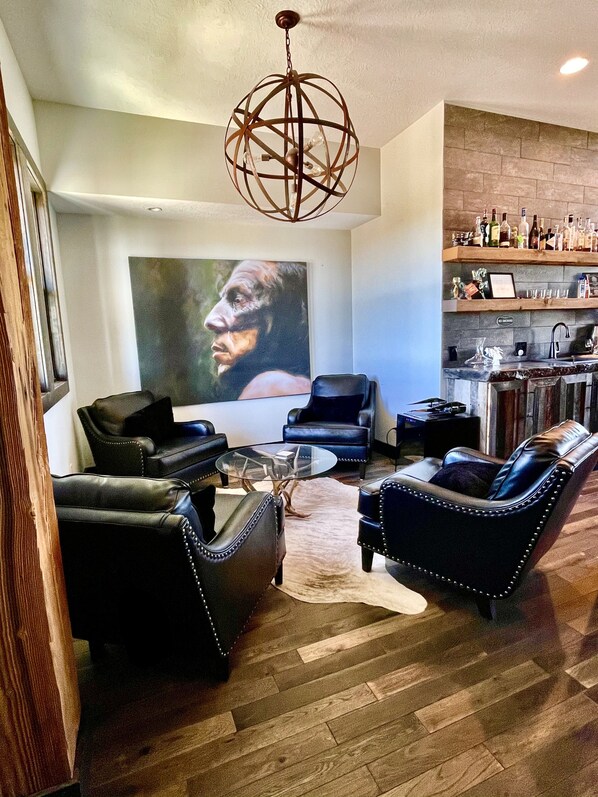 Una sala de estar moderna con sofás de cuero, una mesa de centro de vidrio y un cuadro abstracto de gran tamaño.