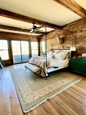 A spacious bedroom with a four-poster bed, a ceiling fan, and a deer head decoration.