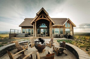 Un moderno lodge con un amplio patio, mobiliario exterior y vistas del paisaje circundante.