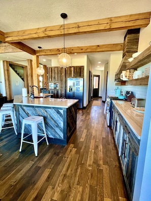 A spacious kitchen with wooden beams, a large island, and modern appliances.