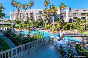 A hotel with a pool area, palm trees, and a view of the ocean.