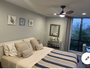 A bedroom with a bed, a nightstand, a mirror, and artwork on the wall.