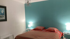 Un dormitorio con una cama, dos mesitas de noche con lámparas, una lámpara de techo y un cuadro en la pared.