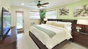 Un dormitorio con cama, escritorio, ventilador de techo y ventana con persianas.