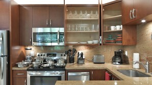 Una cocina moderna con electrodomésticos de acero inoxidable, armarios de madera y encimera de granito.