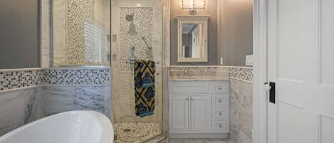 A bathroom with a freestanding bathtub, a walk-in shower, and a vanity with a mirror.