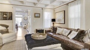 Een ruime woonkamer met een bruine leren bank, een zwart-wit plaid en een plafondventilator.