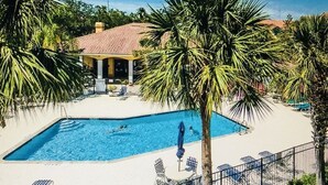 En pool med solstolar och en överbyggd paviljong.