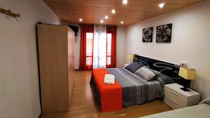Ein Schlafzimmer mit Bett, Nachttischen, einem Kleiderschrank und einem Fenster mit Vorhängen.