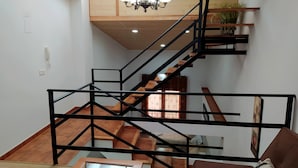 Ein modernes Interieur mit Treppe, Holzböden, einer Kristallleuchtre und einem braunen Ledersofa.