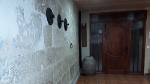 Ein Korridor mit Fliesenboden, einer Holztür und einem an der Wand befestigten Metallgegenstand.