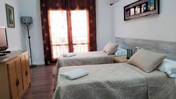 Una camera d'albergo con due letti, una scrivania, una lampada e un quadro appeso al muro.