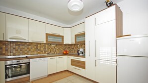 A modern kitchen with white cabinets, a tiled backsplash, and a built-in oven. - Apartment Ana Put Makra (Makarska)