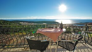 A balcony with a table and chairs, overlooking a scenic view of a body of water and distant landscape. - Apartment Ana Put Makra (Makarska)