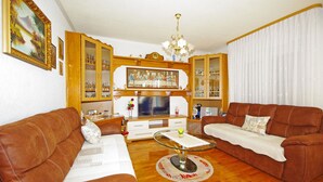 A living room with two brown leather sofas, a glass coffee table, wooden cabinets, and a television. - Apartment Ana Put Makra (Makarska)