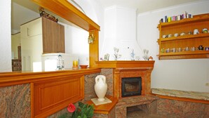 A living room with a fireplace, wooden shelves, and a kitchen area in the background. - Apartment Ana Put Makra (Makarska)