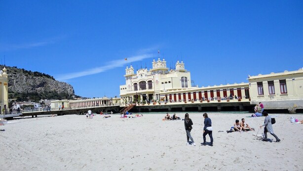 Een strand met een groot, versierd gebouw op de achtergrond.