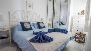 A neatly made bed with blue bedding and pillows, a white headboard, a bedside table with a lamp, and a large mirror cabinet. - Seaview Coastal Home on front line with amazing sea views and large terrace (Puerto del Carmen)