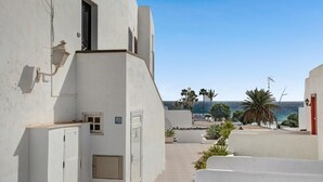 A narrow street with white buildings, a red door, and a view of the sea. - Apartment the Quintero (Tías)
