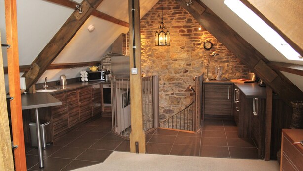 A kitchen with a stone wall, wooden beams, and a skylight.