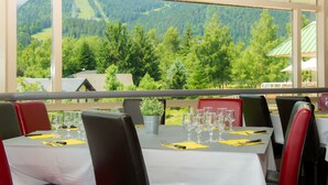 A restaurant with tables set for dining, chairs, and a view of a mountainous landscape. - Village Vacances le Tarbesou - Appartments (Ax-les-Thermes)