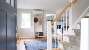 A modern interior with a wooden staircase, a blue rug, and a white bench with hats and bags. - Spectacular quiet location with partial view of Paddy Creek iKennebunkport! (Kennebunkport)