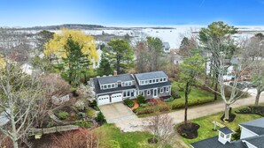 A two-story house with a garage, surrounded by a well-maintained lawn and trees. - Spectacular quiet location with partial view of Paddy Creek iKennebunkport! (Kennebunkport)