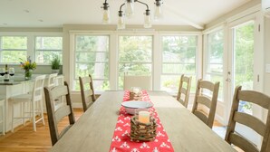 A dining area with a long table, chairs, and a chandelier. - Spectacular quiet location with partial view of Paddy Creek iKennebunkport! (Kennebunkport)