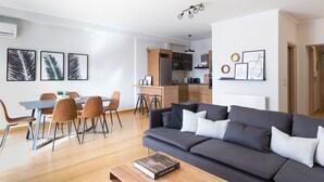 A modern living room with a grey sofa, wooden coffee table, and a dining area with a table and chairs. - UPSTREET Stylish & Spacious 2BD Apt-Thiseio (Athens)
