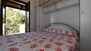 Un dormitori amb un llit, una finestra i vista a arbres.